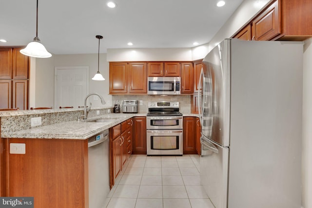 kitchen with a peninsula, stainless steel appliances, brown cabinetry, and a sink