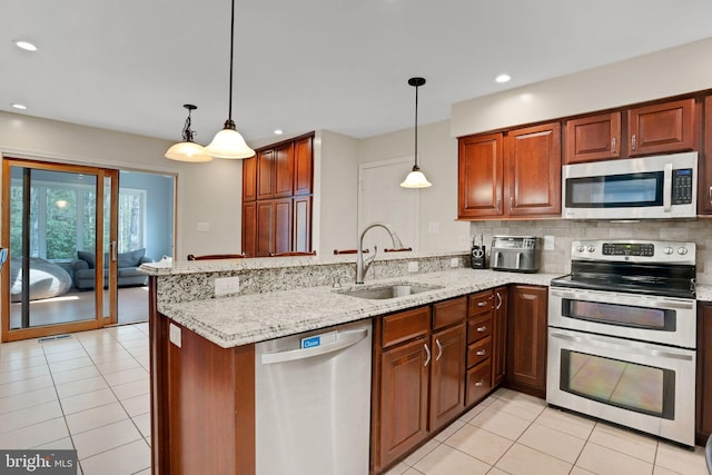 kitchen with light tile patterned floors, light stone counters, a sink, a peninsula, and stainless steel appliances