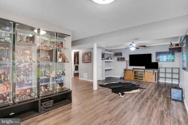 living room featuring a ceiling fan, baseboards, a textured ceiling, and wood finished floors