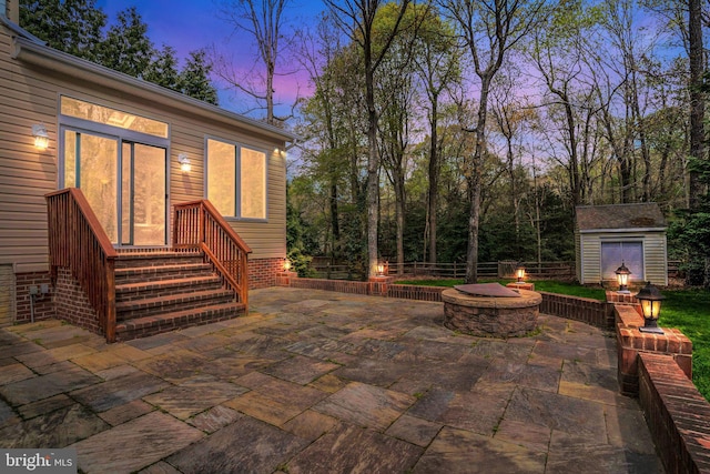view of patio with an outdoor fire pit, an outbuilding, and fence