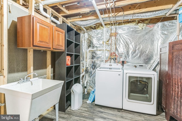 washroom featuring a sink, cabinet space, independent washer and dryer, and wood finished floors