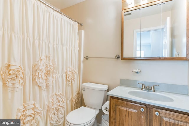 bathroom with vanity, toilet, a shower with curtain, and visible vents