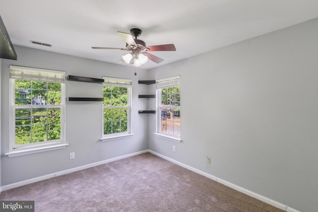 spare room with carpet, visible vents, baseboards, and a ceiling fan