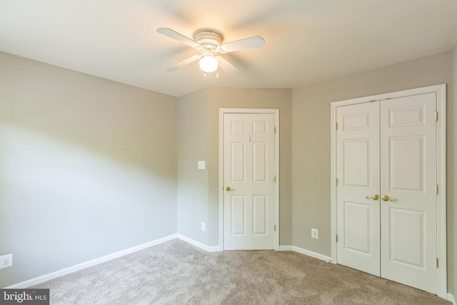 unfurnished bedroom with carpet, a closet, baseboards, and a ceiling fan