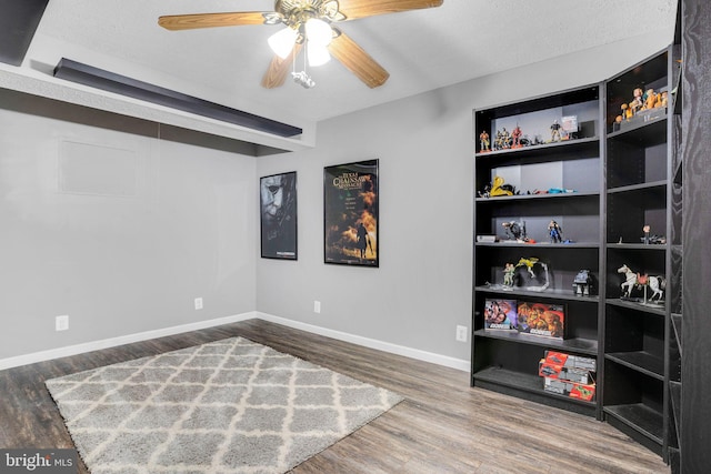 interior space with baseboards, ceiling fan, and wood finished floors