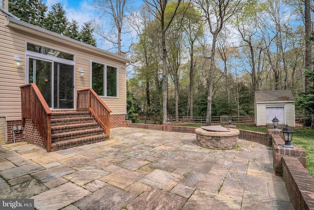 view of patio / terrace featuring an outdoor fire pit, an outbuilding, a storage shed, and fence