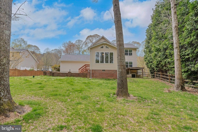 back of house featuring a lawn, fence, and crawl space