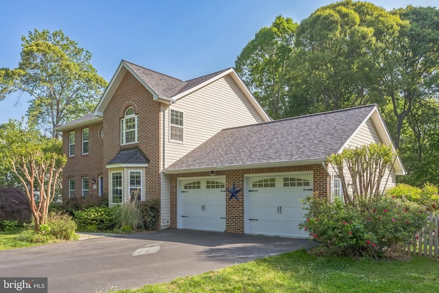 view of side of home featuring roof with shingles, an attached garage, and brick siding