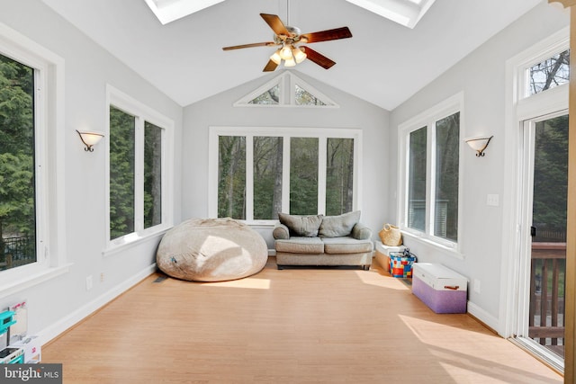 sunroom / solarium featuring baseboards, vaulted ceiling with skylight, and wood finished floors