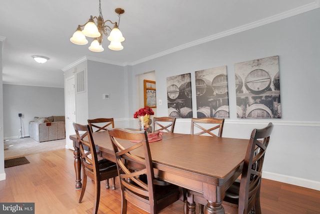 dining space featuring wood finished floors, visible vents, a chandelier, crown molding, and baseboards