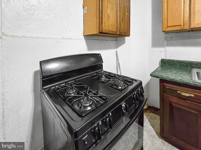 1837 W Juniata St, Philadelphia, PA 19140 - kitchen with black range with gas cooktop, dark countertops, and brown cabinetry