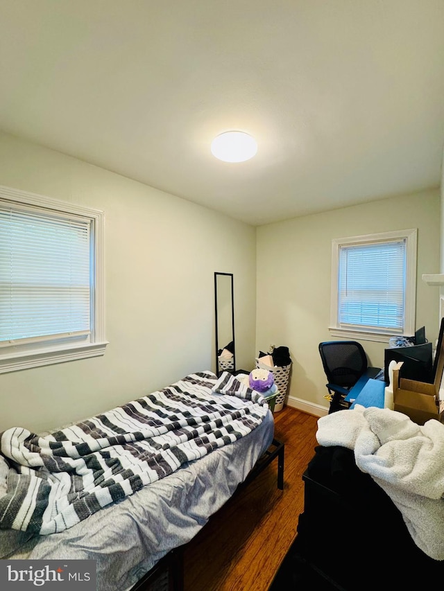bedroom with dark wood-style flooring, multiple windows, and baseboards