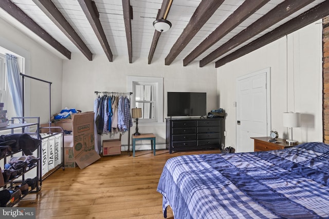 bedroom featuring beam ceiling and light wood-style flooring