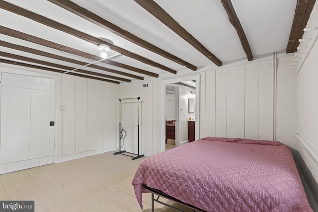 bedroom with light wood finished floors and beamed ceiling