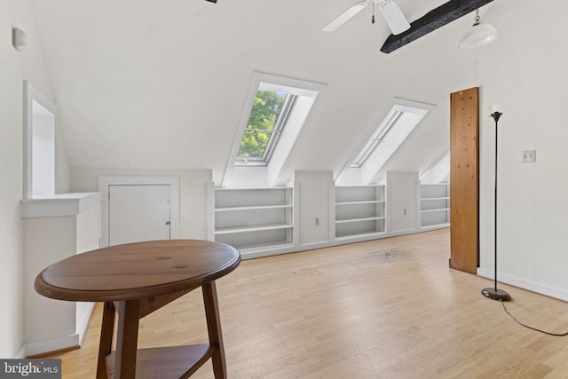 additional living space featuring ceiling fan, lofted ceiling with skylight, baseboards, and wood finished floors