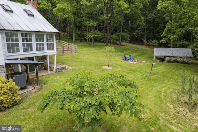 view of yard featuring a wooded view, an outdoor structure, and central AC