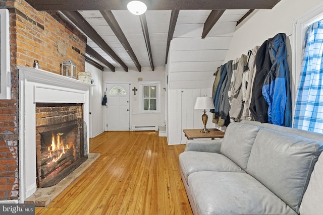 living area with light wood-style floors, baseboard heating, a fireplace, and beam ceiling