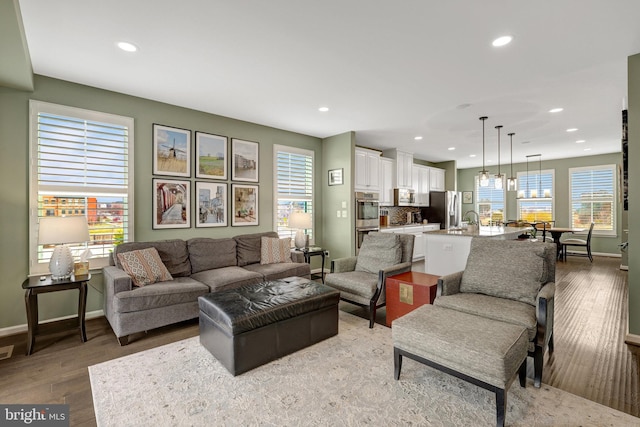 living area with recessed lighting, healthy amount of natural light, baseboards, and light wood-type flooring