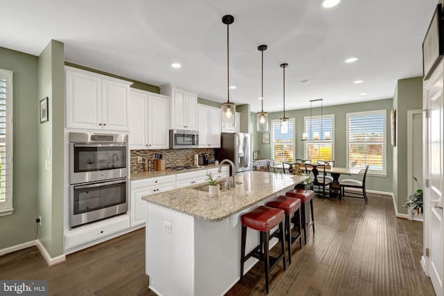 kitchen featuring a sink, stainless steel appliances, a kitchen island with sink, baseboards, and recessed lighting
