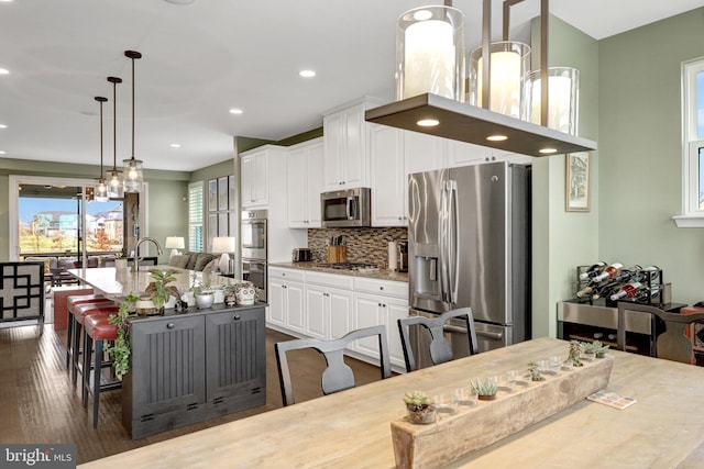 kitchen with stainless steel appliances, white cabinets, decorative backsplash, light stone countertops, and recessed lighting