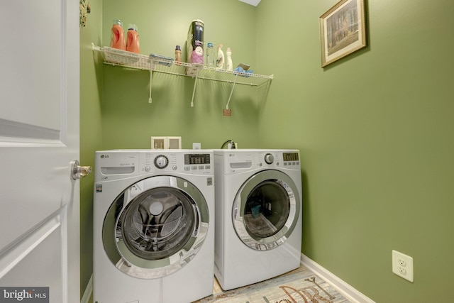 washroom featuring washer and dryer, baseboards, and wood finished floors