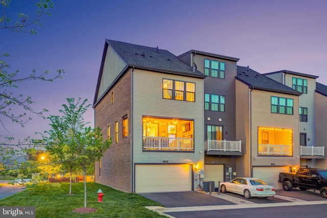multi unit property featuring an attached garage, driveway, and a lawn