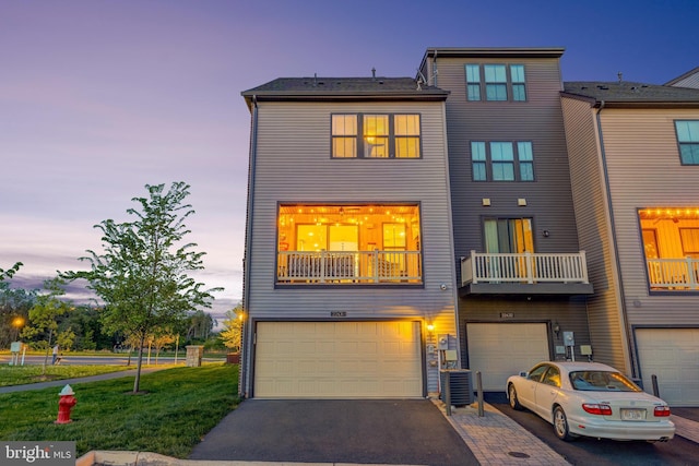 townhome / multi-family property featuring a garage, driveway, central air condition unit, and a yard