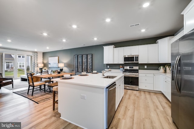 kitchen featuring a sink, stainless steel appliances, a kitchen island with sink, light wood-type flooring, and visible vents