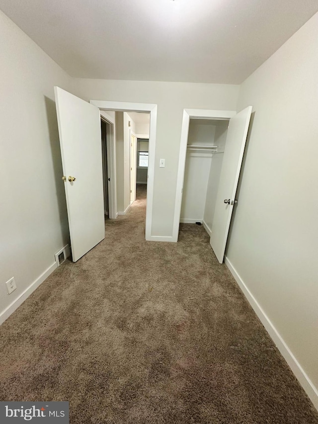 unfurnished bedroom with carpet flooring, baseboards, and visible vents