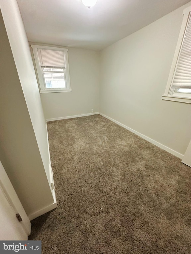 carpeted empty room featuring baseboards