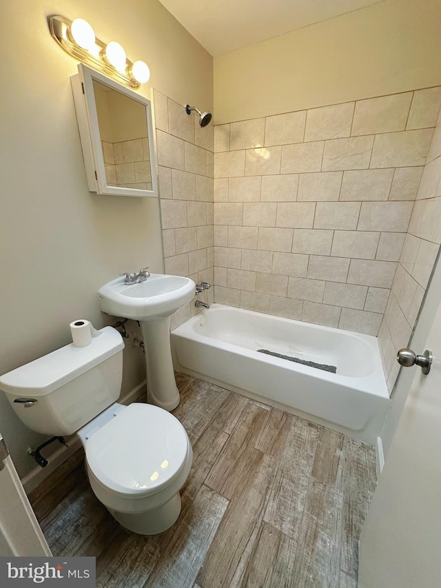 bathroom with toilet, wood finished floors, and shower / bathtub combination