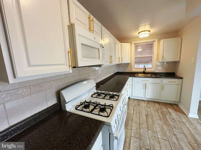 kitchen featuring a sink, dark countertops, light wood-type flooring, white appliances, and tasteful backsplash