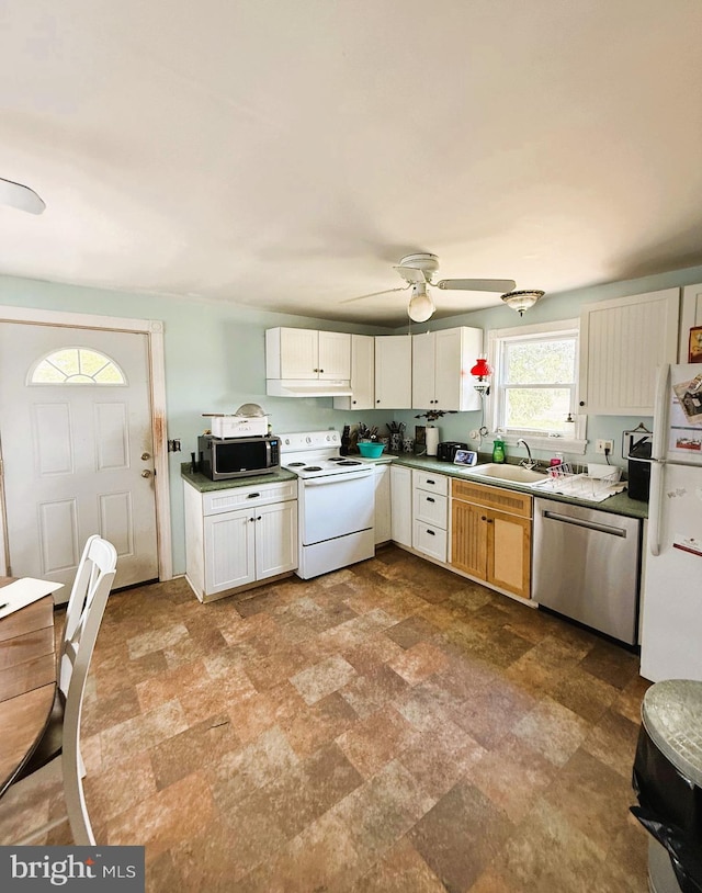 kitchen with a sink, stainless steel appliances, a ceiling fan, and stone finish floor