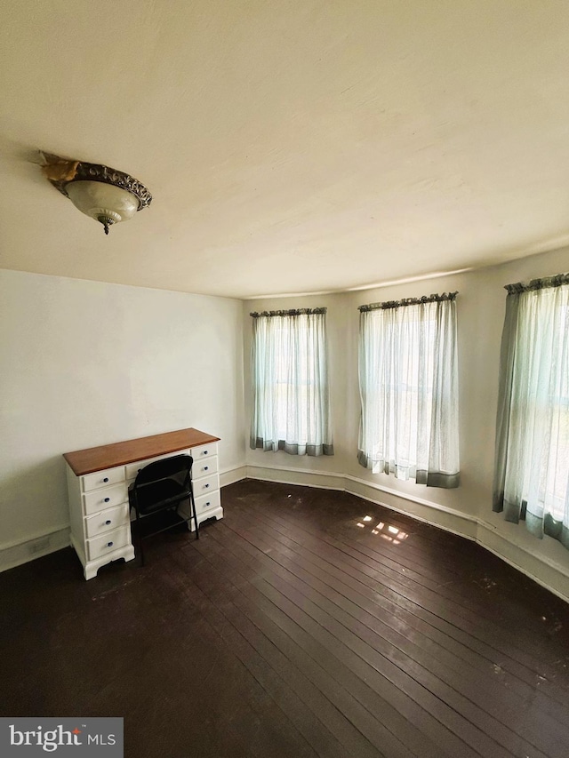 unfurnished office featuring baseboards and dark wood finished floors