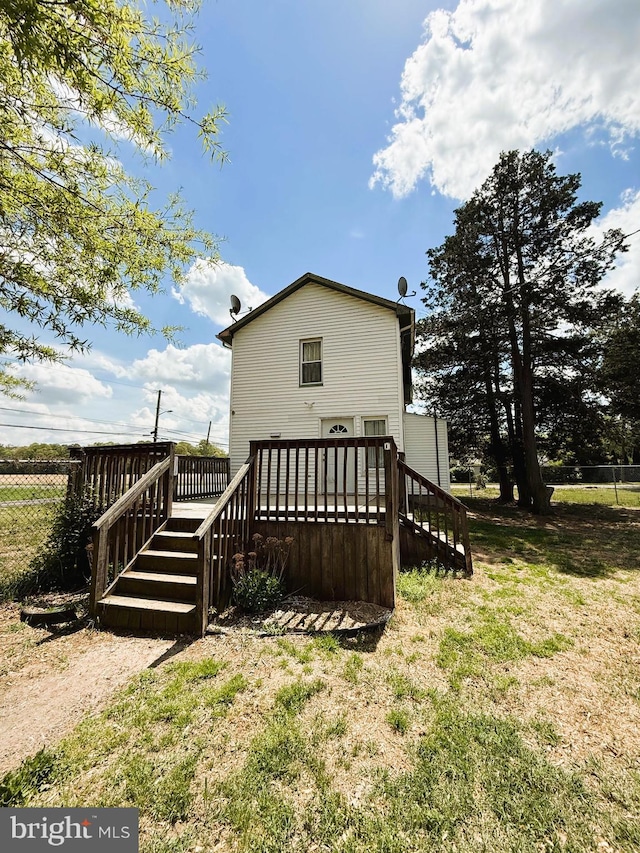 back of property featuring a deck, stairs, fence, and a lawn