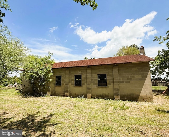 exterior space with a chimney and a lawn