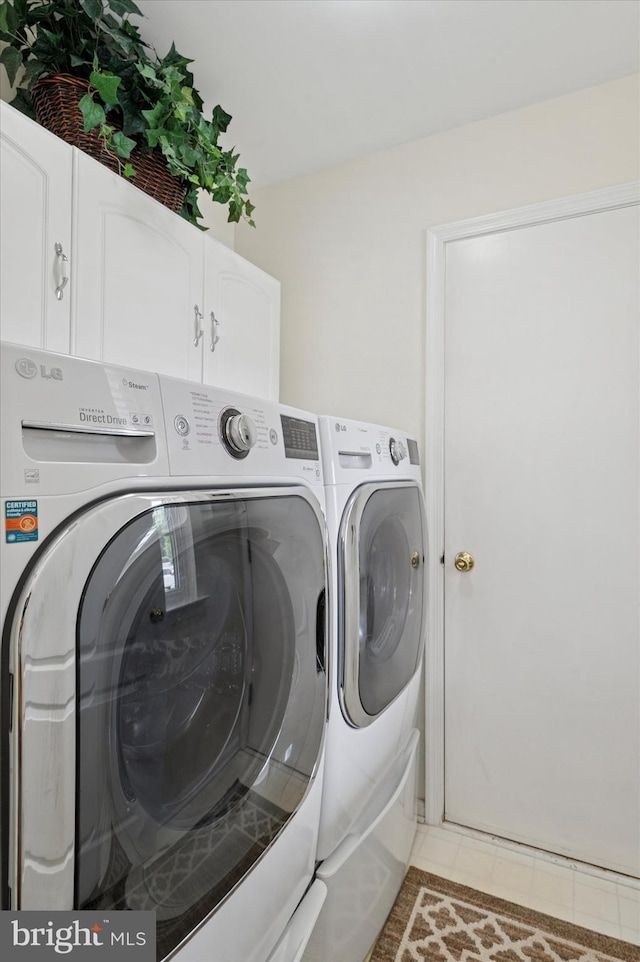 clothes washing area featuring washer and dryer, cabinet space, and light tile patterned flooring