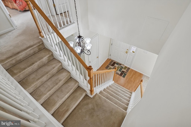 stairway with wood finished floors and a chandelier