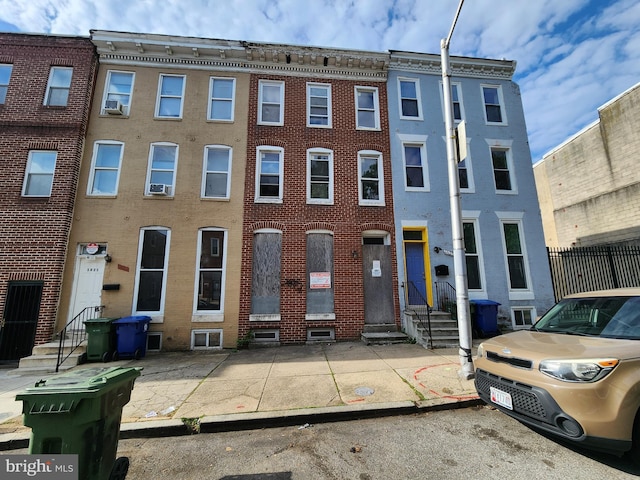 townhome / multi-family property with cooling unit and brick siding