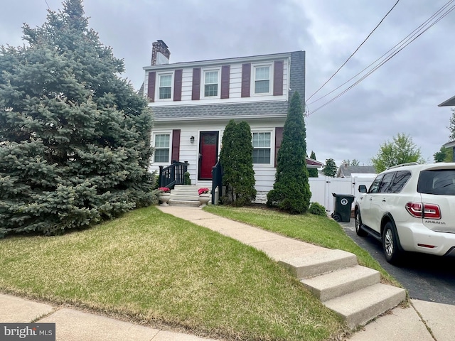 view of front of home featuring fence, a chimney, and a front yard