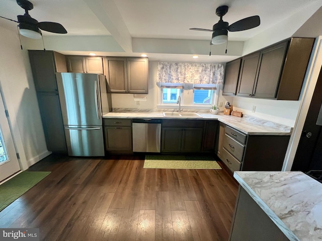 kitchen with a sink, stainless steel appliances, ceiling fan, dark wood-style flooring, and light countertops