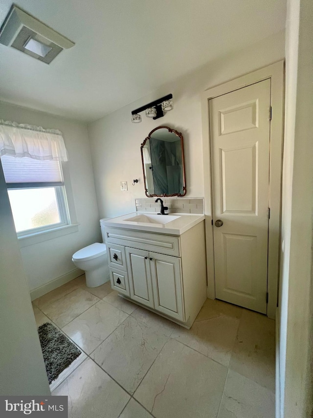 bathroom featuring toilet, marble finish floor, and vanity