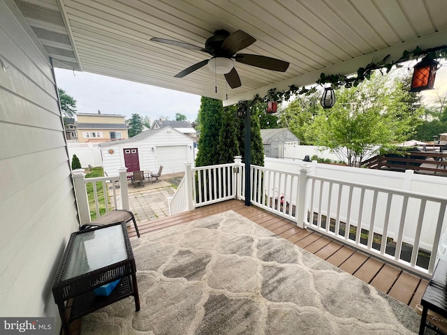 view of patio / terrace featuring an outdoor structure, a ceiling fan, fence, and a deck