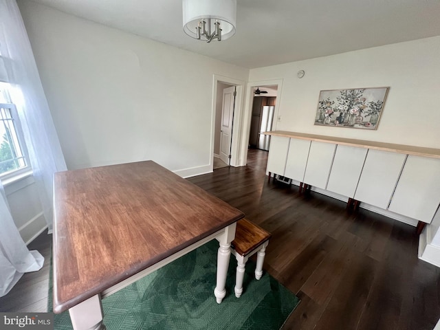 dining space with an inviting chandelier, dark wood-type flooring, and baseboards