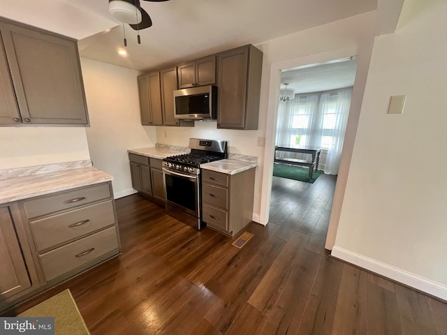 kitchen with appliances with stainless steel finishes, baseboards, ceiling fan, and dark wood-style floors