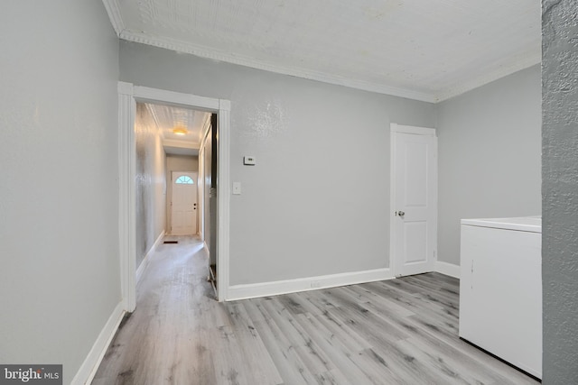 unfurnished room featuring washer / clothes dryer, ornamental molding, wood finished floors, and baseboards