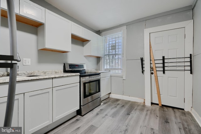 kitchen with stainless steel range with electric stovetop, light wood finished floors, white cabinetry, light stone countertops, and a sink