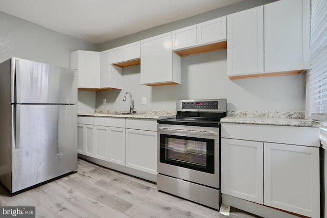 kitchen with appliances with stainless steel finishes, light wood-type flooring, white cabinets, and light stone counters