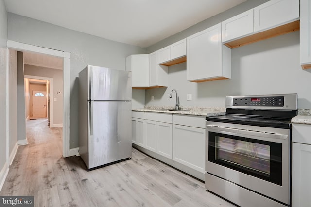kitchen with appliances with stainless steel finishes, a sink, light wood-style flooring, and white cabinetry