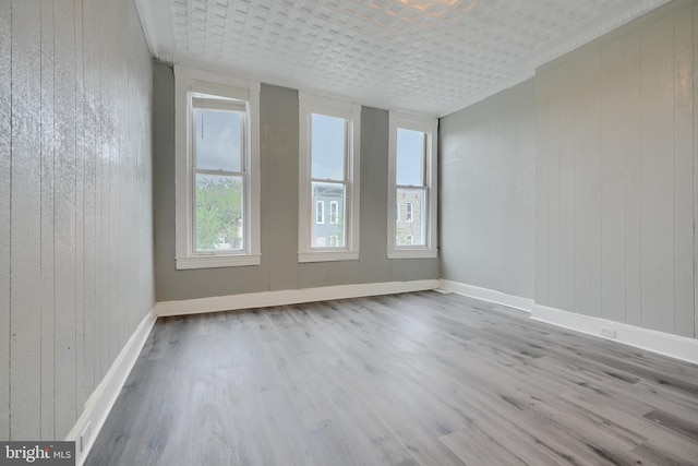 unfurnished room featuring wood finished floors, baseboards, and wooden walls